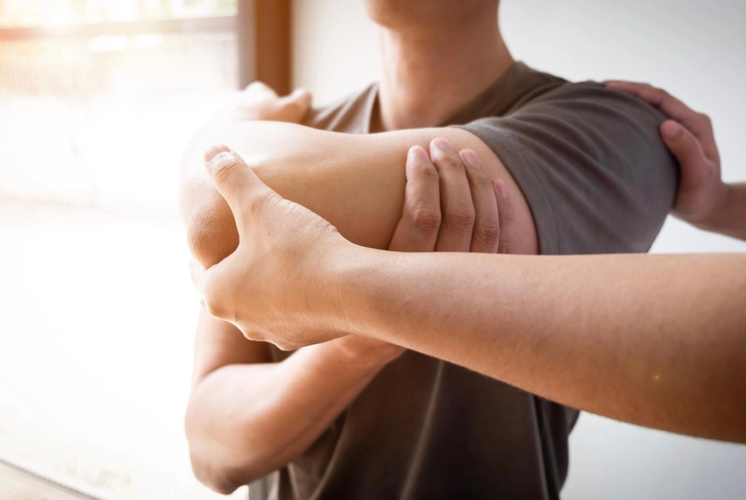 Physiotherapie Claudine König - Heilpraktikerin Physiotherapie - Ein Physiotherapeut oder -praktiker leitet einen Mann durch eine sitzende Schulter- und Armdehnübung.